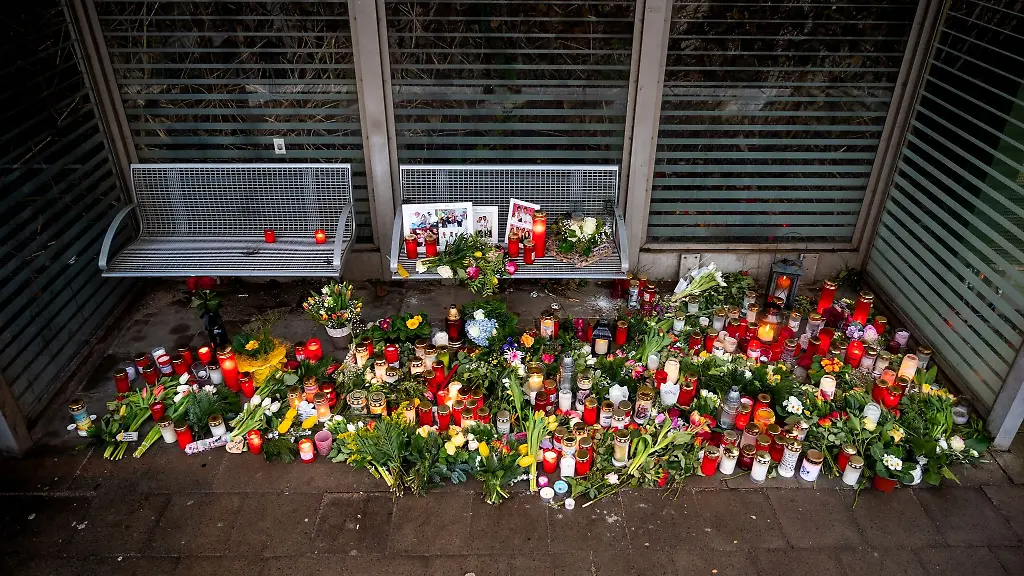 Kerzen-und-Blumen-stehen-und-liegen-im-Bahnhof-Brokstedt-in-einem-Wartehaeuschen