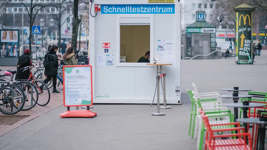 Passanten-gehen-in-der-Innenstadt-an-einem-Corona-Testzentrum-vorbei