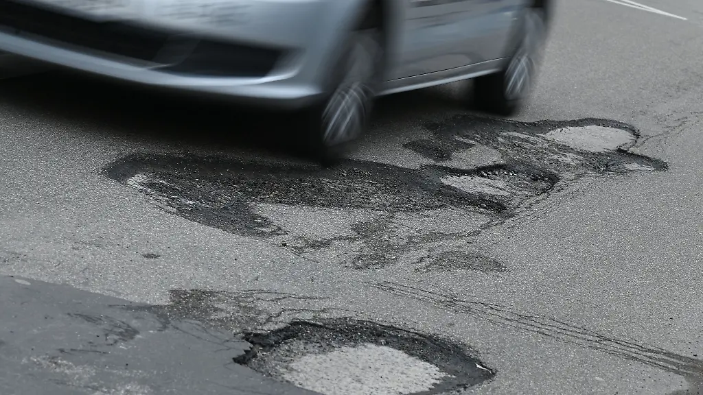 Ein-Auto-faehrt-durch-ein-Schlagloch