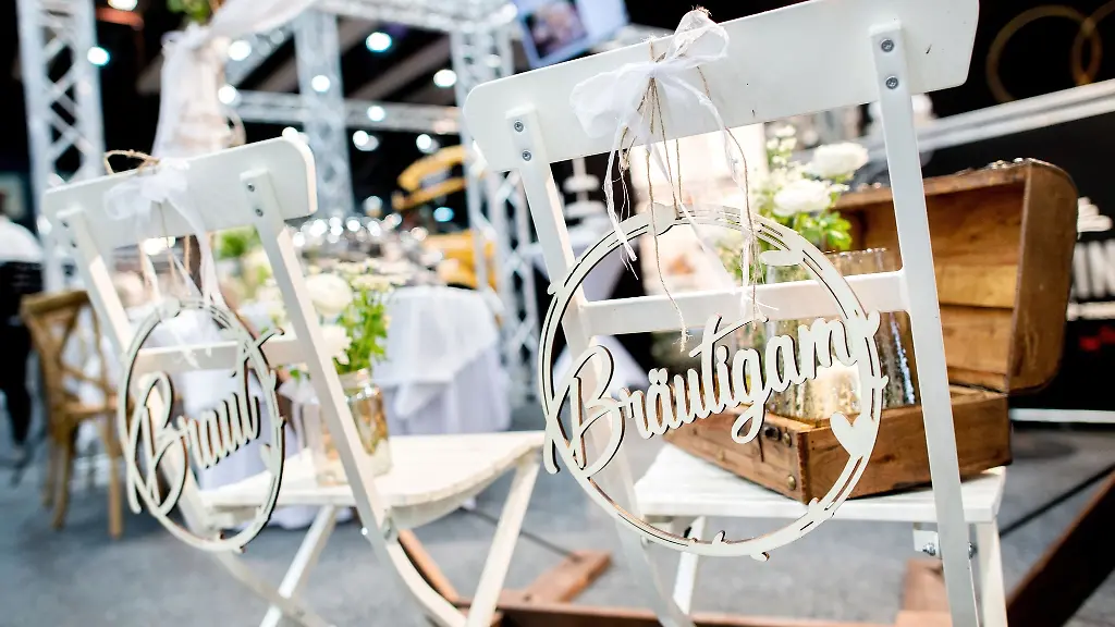 Zwei-Stuehle-fuer-eine-Hochzeitsfeier-stehen-auf-der-Hochzeitsmesse-an-einem-Stand