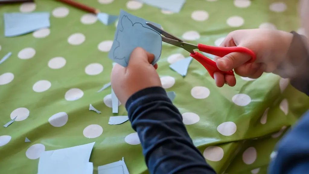 Ein-Kind-schneidet-waehrend-der-Freizeitbetreuung-Papier-aus