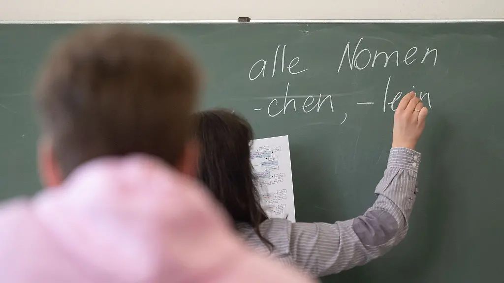 Ein-Lehrerin-schreibt-im-Unterricht-etwas-an-die-Tafel