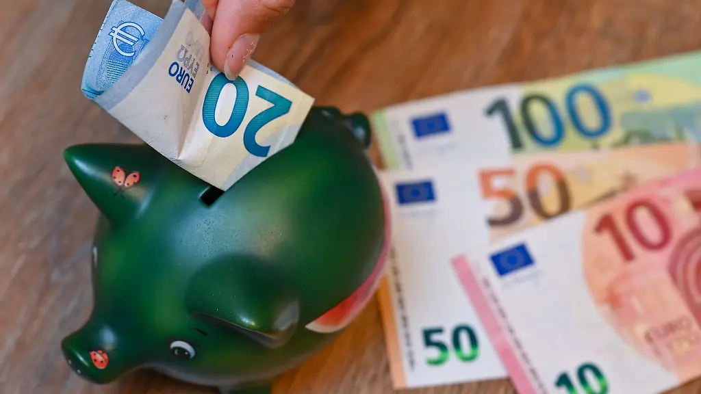 Ein-Maedchen-steckt-einen-20-Euro-Schein-in-ein-Sparschwein
