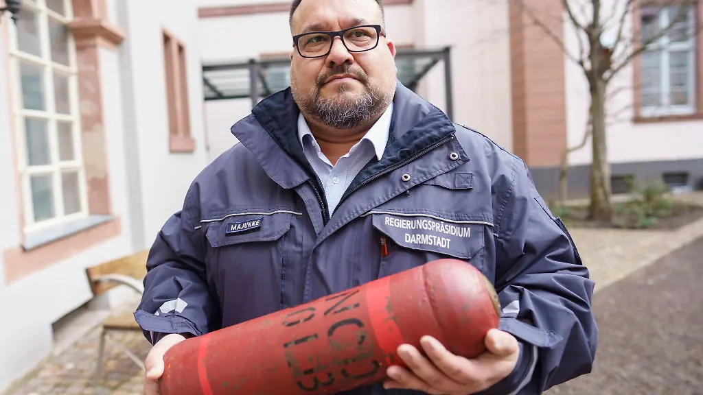 Alexander-Majunke-Leiter-des-Kampfmittelraeumdienstes-des-Landes-Hessen-steht-im-Hof-des-Regierungspraesidiums-mit-einer-zu-Schulungszwecken-entschaerften-und-entleerten-Brandbombe
