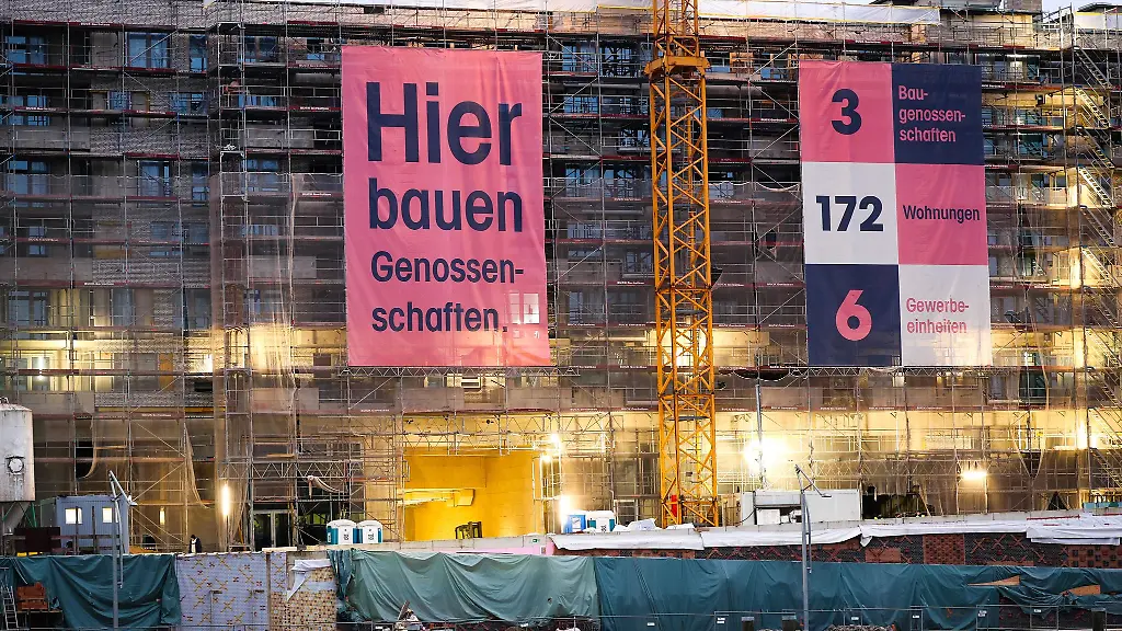 Hier-bauen-Genossenschaften-steht-auf-einem-grossen-Banner-an-einem-Baugeruest-auf-einer-Baustelle-in-der-Hafencity