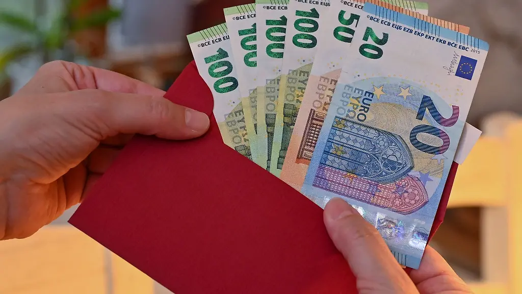 Eine-Frau-steckt-Eurobanknoten-in-einen-Umschlag