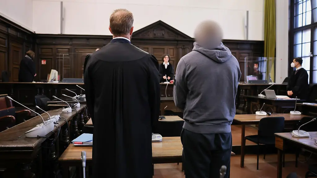 Der-Angeklagte-r-und-sein-Anwalt-stehen-zu-Prozessbeginn-im-Gerichtssaal