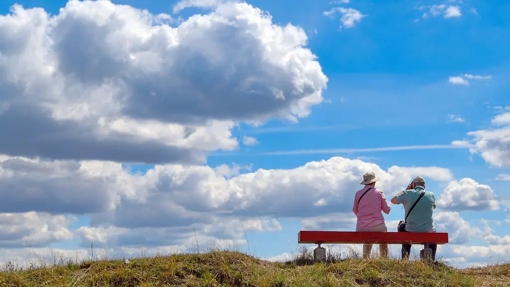 Zwei-aeltere-Personen-sitzen-auf-einer-Bank-in-der-Natur