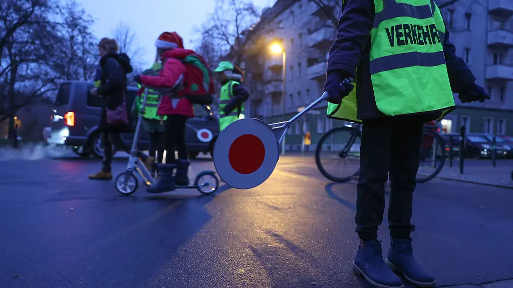 Schuelerlotsen-einer-Grundschule-sorgen-an-einer-Kreuzung-dafuer-dass-Schulkinder-sicher-die-Strasse-ueberqueren-koennen