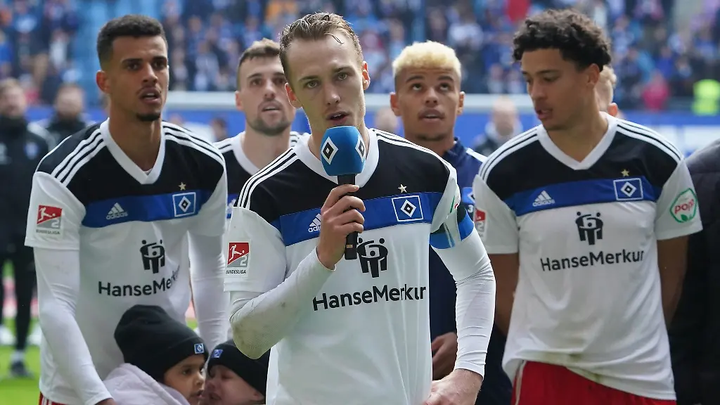 Hamburgs-Kapitaen-Sebastian-Schonlau-und-seine-Mannschaftskollegen-jubeln-nach-Spielende-ihren-Fans-in-der-Nordkurve-zu