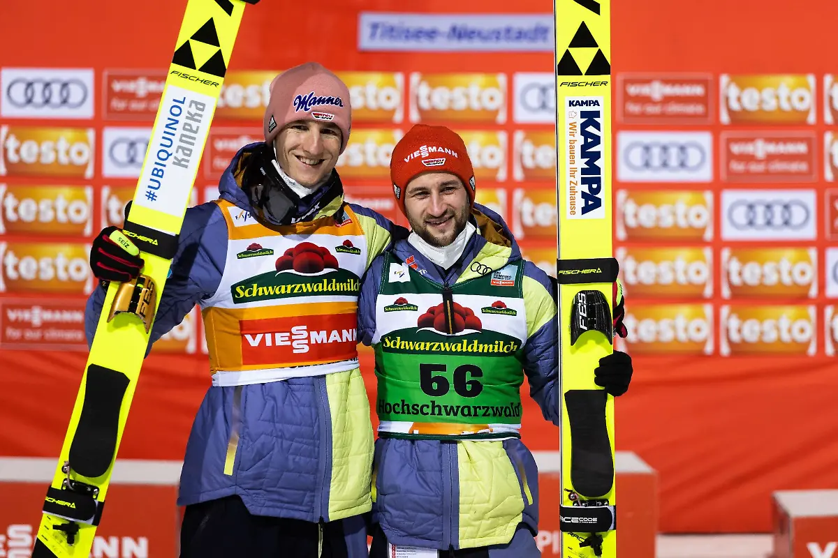 Karl-Geiger-l-und-Teamkollege-Markus-Eisenbichler-stehen-nebeneinander-und-posieren-fuer-die-Fotografen