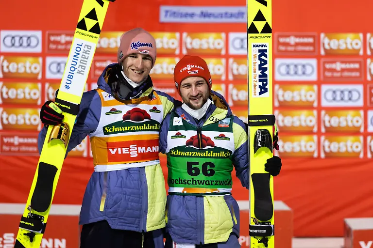 Karl-Geiger-l-und-Teamkollege-Markus-Eisenbichler-stehen-nebeneinander-und-posieren-fuer-die-Fotografen