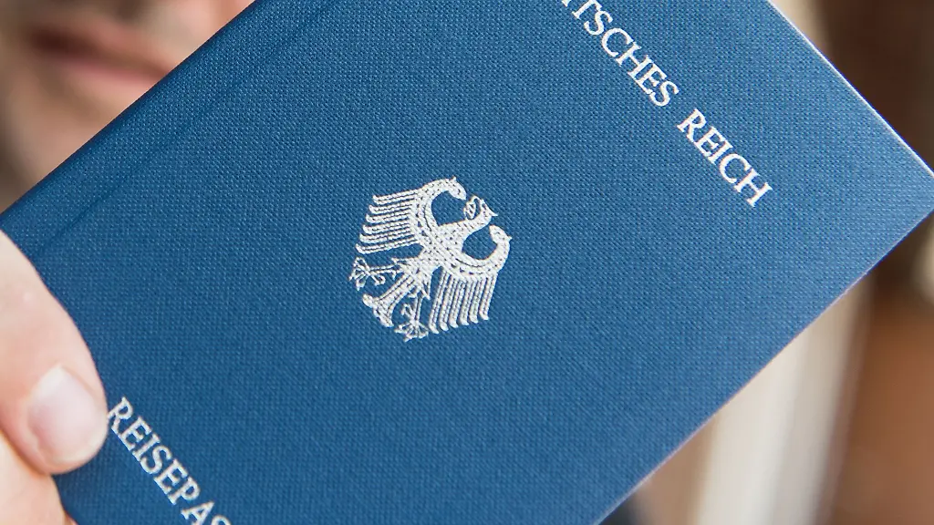 Ein-Mann-haelt-ein-Heft-mit-dem-Aufdruck-Deutsches-Reich-Reisepass-in-der-Hand