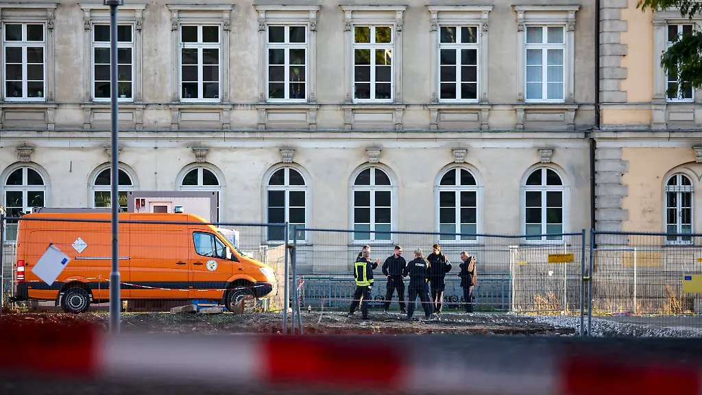 Mitglieder-von-Polizei-Kampfmittelraeumdienst-und-Feuerwehr-stehen-hinter-der-Absperrung-an-einer-Baustelle