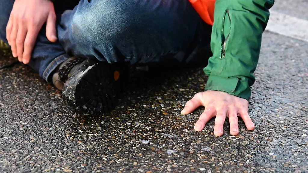 Ein-Aktivist-hat-sich-mit-einer-Hand-auf-einer-Strasse-festgeklebt