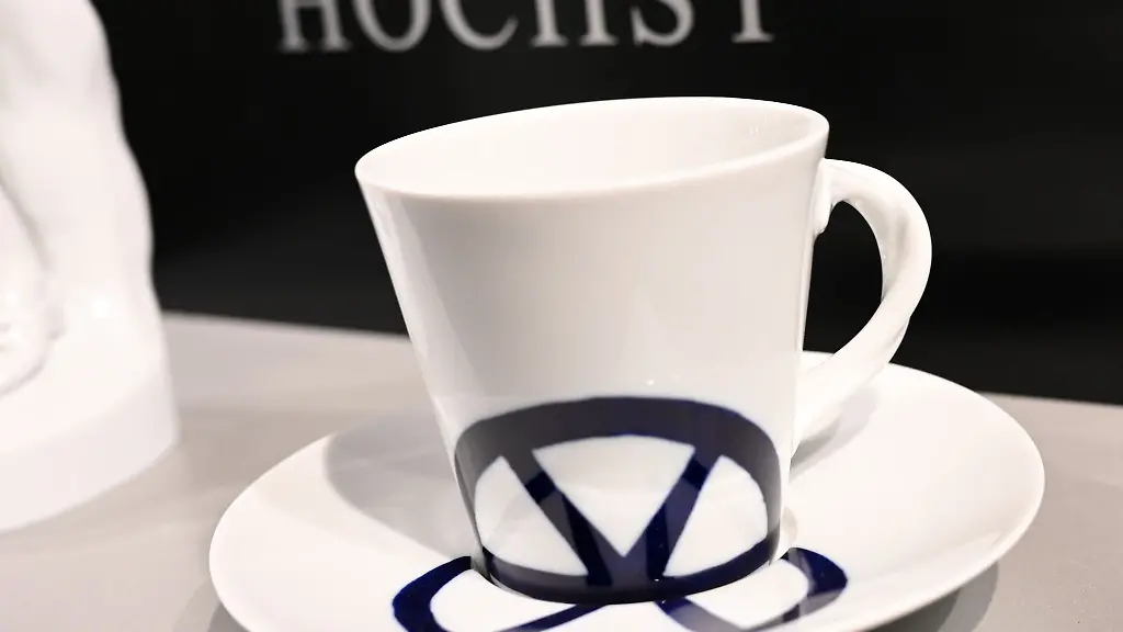 Tasse-und-Untertasse-aus-der-Hoechster-Porzellanmanufaktur-stehen-im-Werksverkauf-vor-dem-Logo-der-Manufaktur