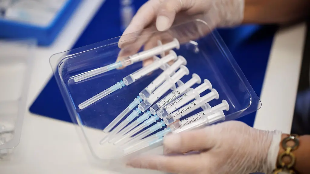 Eine-Krankenschwester-haelt-in-einem-Impfzentrum-eine-Schale-mit-Spritzen-in-den-Haenden