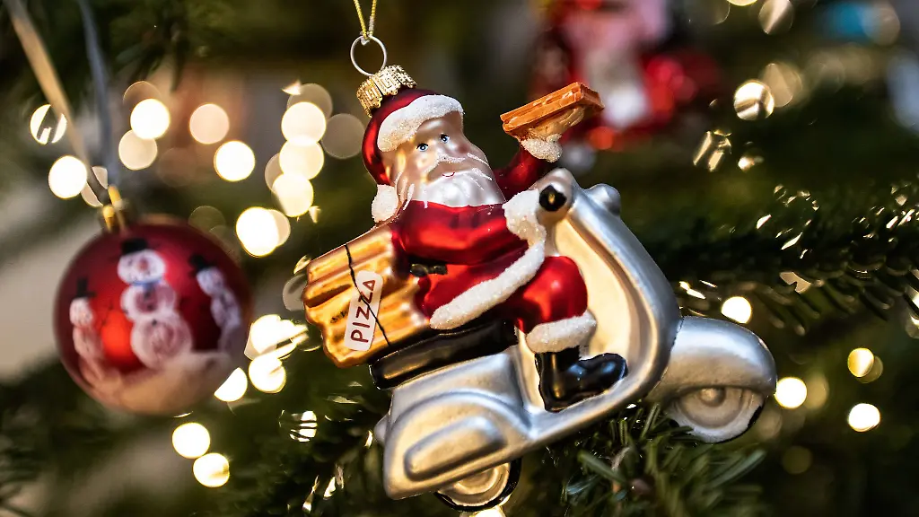 Geschmueckt-ist-ein-Weihnachtsbaum-mit-einer-Weihnachtsmannfigur-auf-einem-Motorrad-einer-Lichterkette-und-Weihnachtskugeln