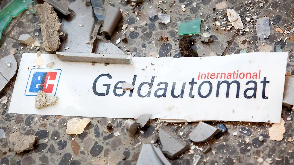Splitter-und-ein-Schild-mit-der-Aufschrift-Geldautomat-liegen-auf-dem-Fussboden-vor-einem-gesprengten-Geldautomaten
