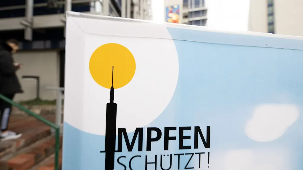 Ein-Plakat-mit-der-Aufschrift-Impfen-schuetzt-steht-vor-einem-Impfzentrum