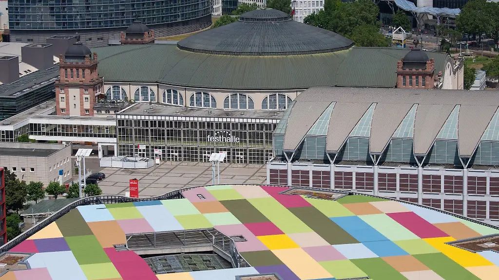 Die-Festhalle-in-Frankfurt-steht-eingebettet-zwischen-Hochhaeusern-und-dem-bunten-Dach-eines-Shopping-Centers