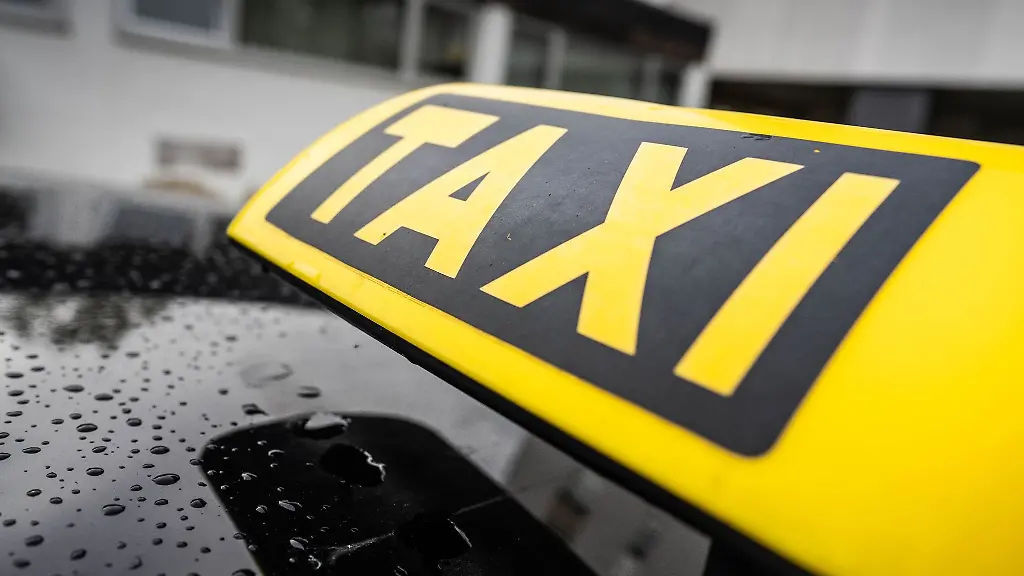 Ein-Taxi-Schild-ist-auf-dem-Dach-eines-Fahrzeuges-befestigt