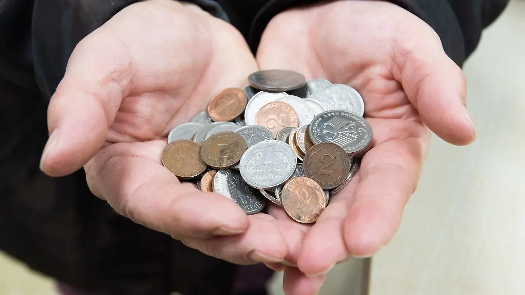 Eine-Kundin-steht-mit-einer-Handvoll-D-Mark-Stuecken-und-Pfennigen-in-einem-Geschaeft