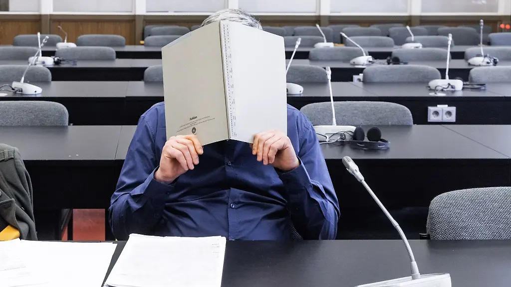 Der-Angeklagte-verbirgt-im-Gerichtssaal-sein-Gesicht-hinter-einem-Aktendeckel