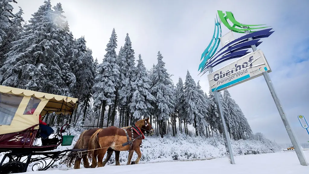 Eine-Pferdekutsche-faehrt-an-einem-Schild-vorbei-das-fuer-Oberhof-im-Thueringer-Wald-wirbt