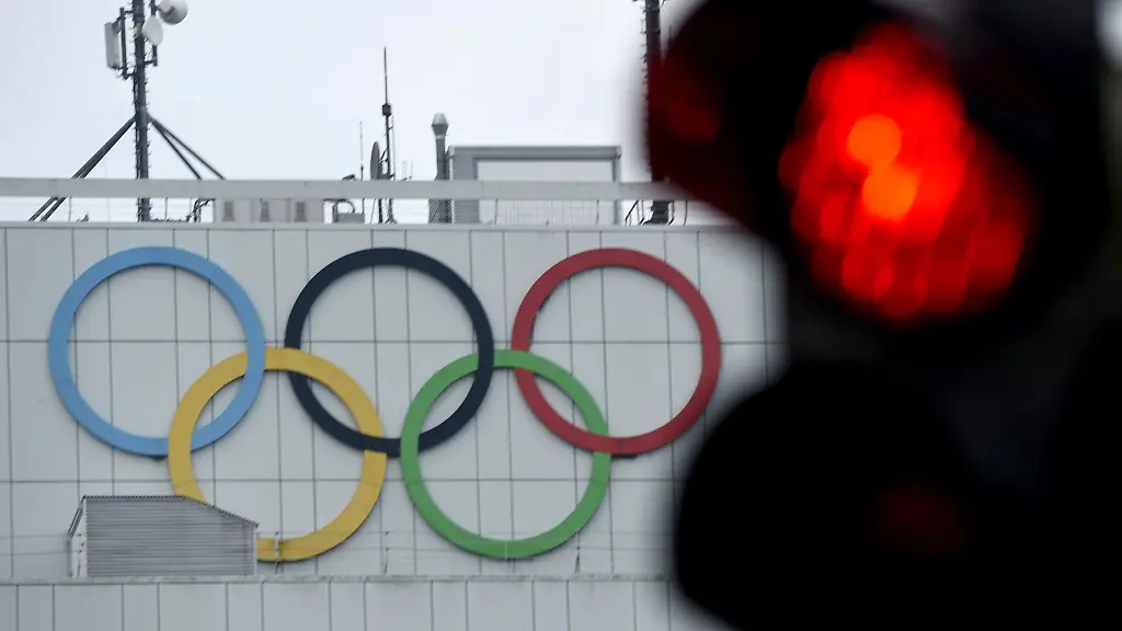 Das-rote-Licht-einer-Ampel-ist-vor-den-Olympischen-Ringen-an-einem-Hochhaus-zu-sehen