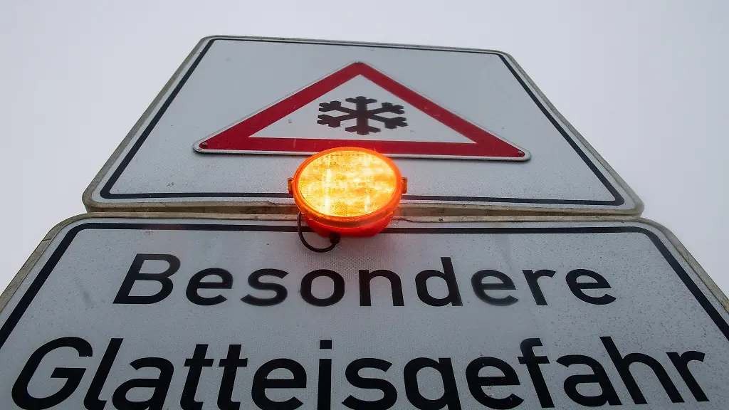 Ein-Strassenschild-warnt-mit-einer-Blinkleuchte-vor-Glatteis