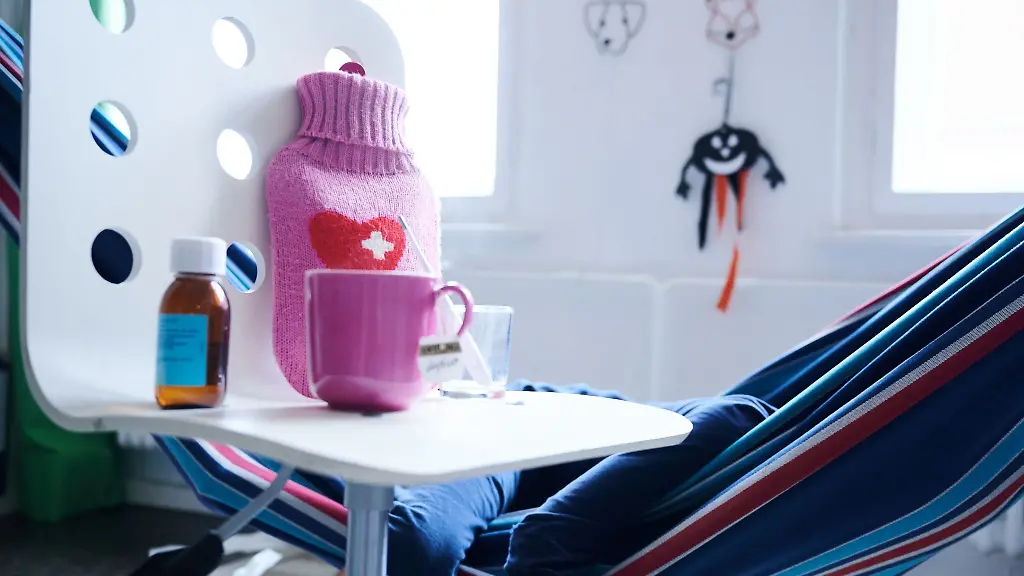 Fieberthermometer-und-Tee-stehen-neben-einem-kranken-Kind