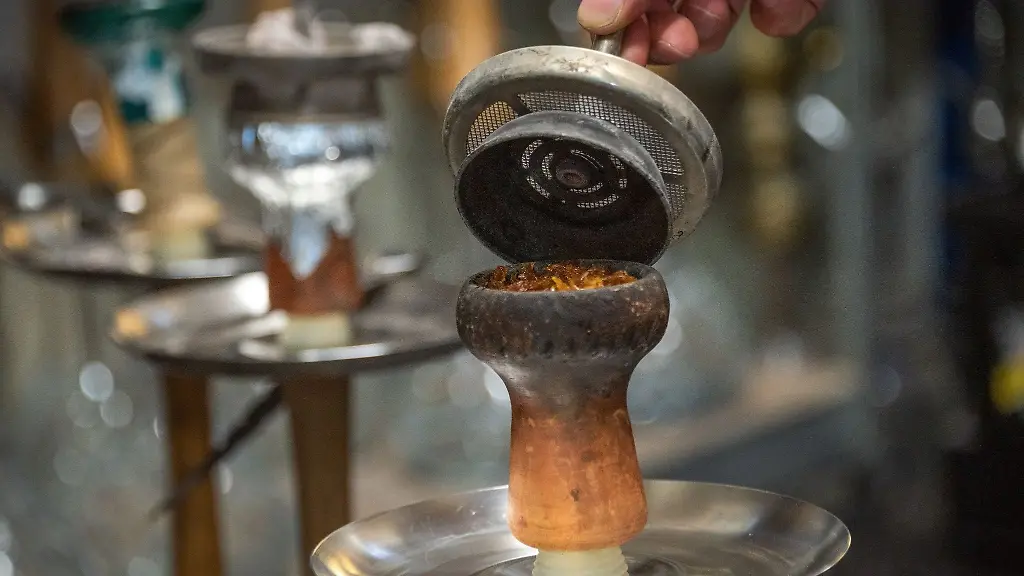 Ein-Mann-fuellt-Tabak-in-den-Kopf-einer-Shisha