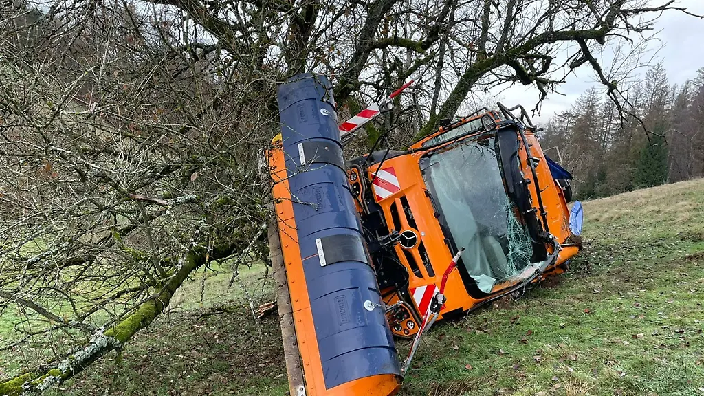 Ein-Schneepflug-des-Winterdienstes-ist-einen-Hang-hinabgerutscht-und-haengt-an-einem-Baum