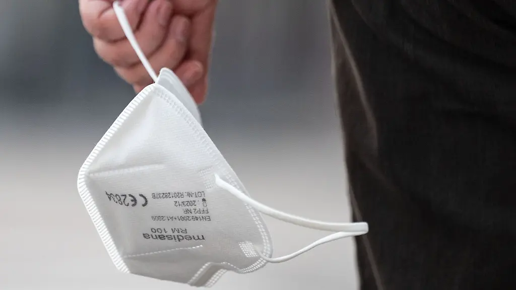 Ein-Passant-traegt-eine-FFP2-Maske-in-der-Hand