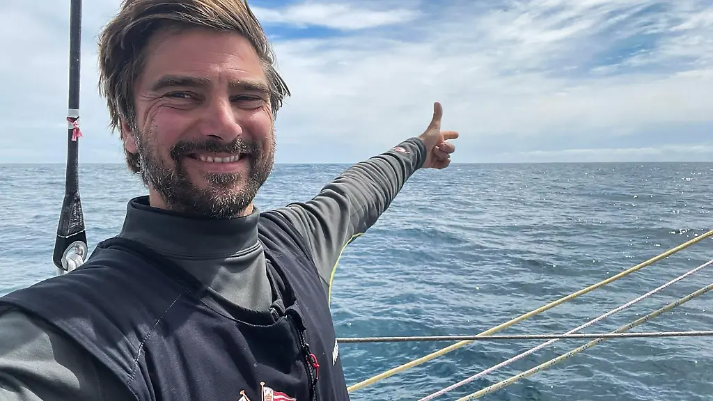 Boris-Herrmann-steht-auf-seiner-Rennyacht-Seaexplorer-Yacht-Club-de-Monaco-und-deutet-aufs-Meer