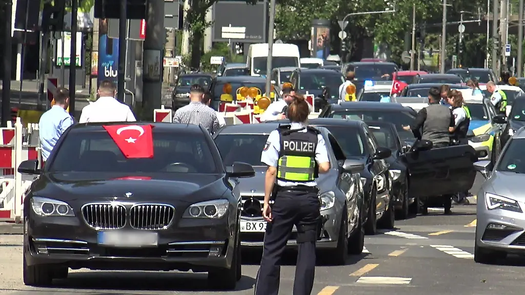 Eine-Polizistin-steht-vor-den-Fahrzeugen-eines-Hochzeitskorsos