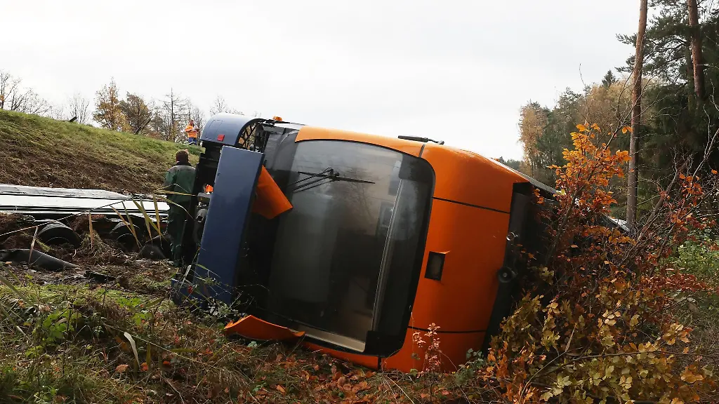 Ein-Schwerlasttransporter-und-ein-Strassenbahnwagen-liegen-unterhalb-der-Autobahn-9-in-einem-Graben