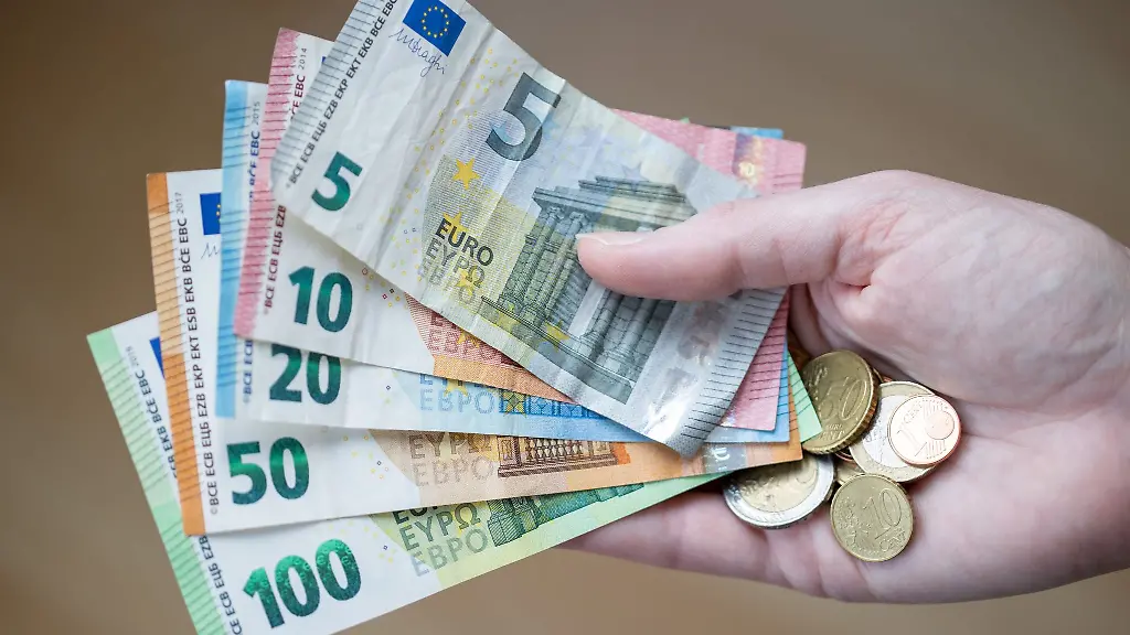 Eine-Frau-haelt-Geldscheine-und-Muenzen-in-der-Hand