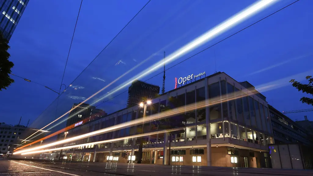 Lichtspuren-einer-vorbeifahrenden-Strassenbahn-sind-am-Abend-vor-Oper-r-und-Schauspiel-in-Frankfurt-zu-sehen