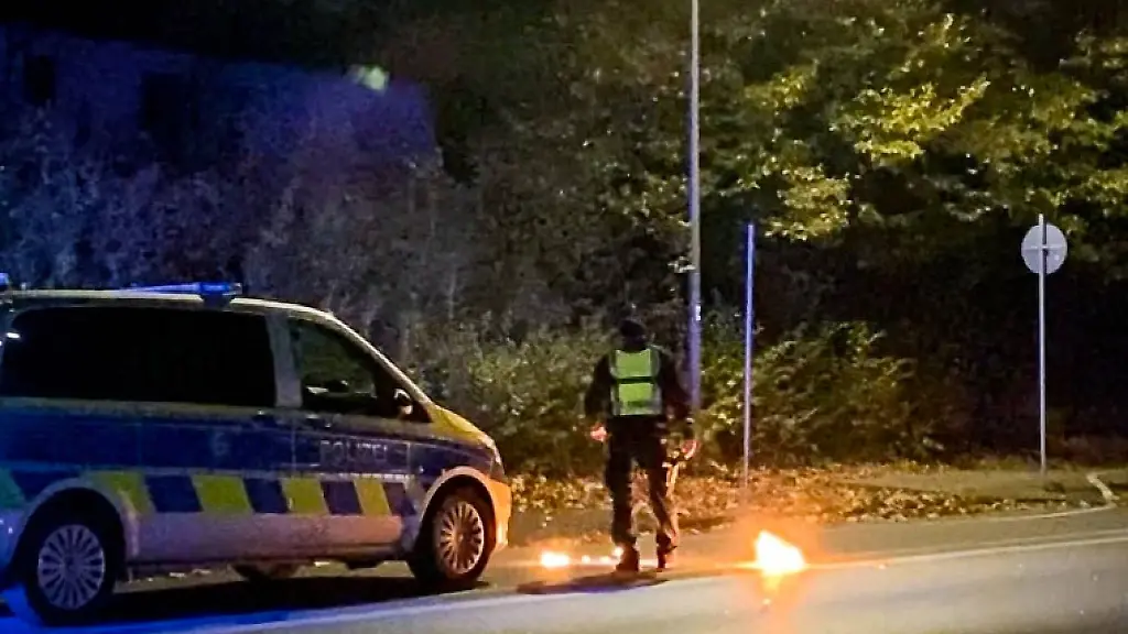 Ein-Polizist-steht-bei-dem-Feuer-vor-einem-Streifenwagen