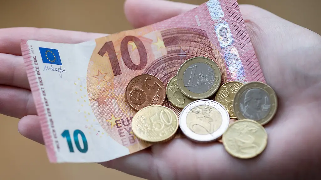 Eine-Frau-haelt-Geldscheine-und-Muenzen-in-der-Hand