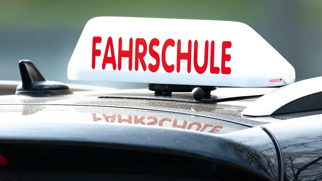 Ein-Dachschild-mit-der-Aufschrift-Fahrschule-ist-auf-einem-Fahrschulauto-befestigt