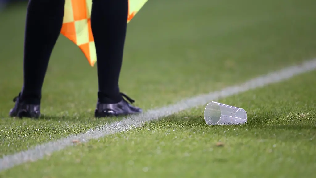 Ein-leerer-Becher-liegt-neben-einem-Schiedsrichter-Assistenten-auf-dem-Rasen