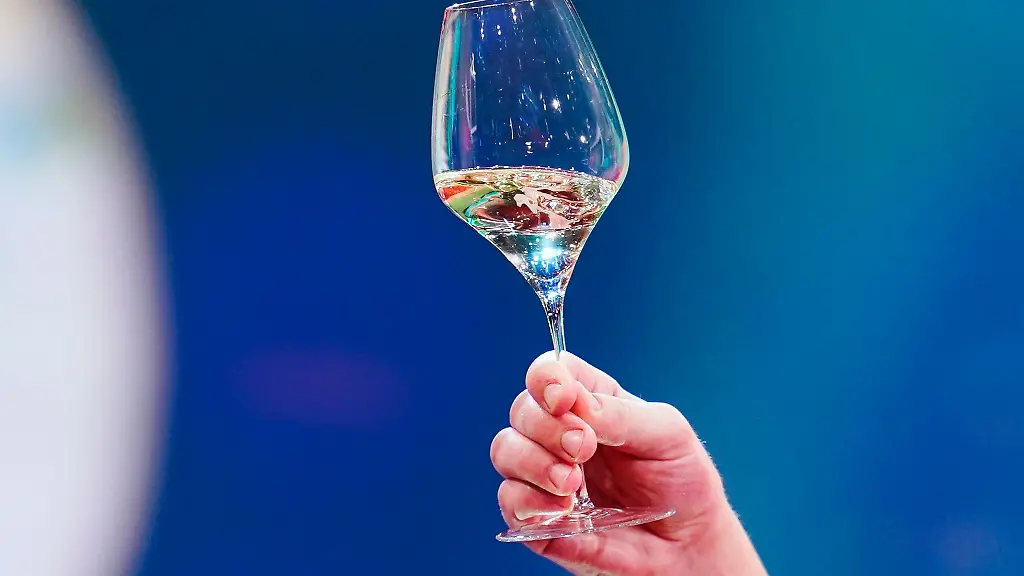 Eine-Frau-haelt-ein-Glas-mit-Weisswein-in-der-Hand