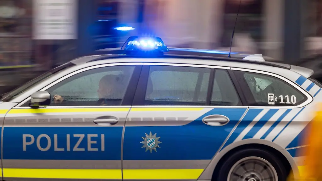 Ein-Fahrzeug-der-bayerischen-Polizei-faehrt-mit-Blaulicht-durch-die-Innenstadt