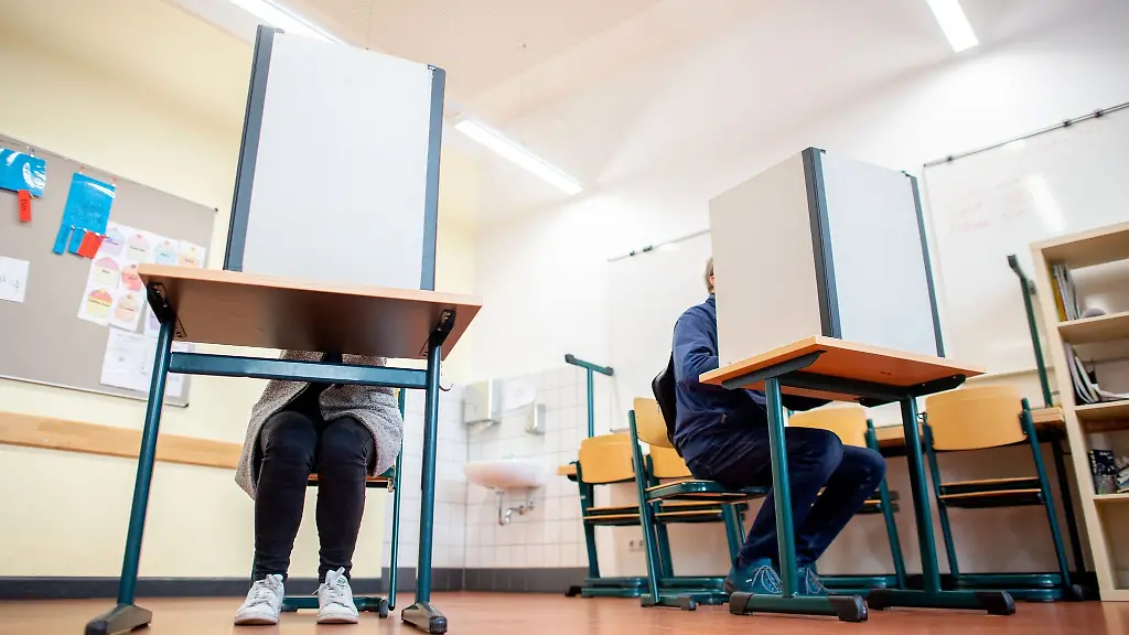 Waehler-sitzen-in-einem-Wahlraum-in-der-Lutherschule-hinter-einem-Sichtschutz