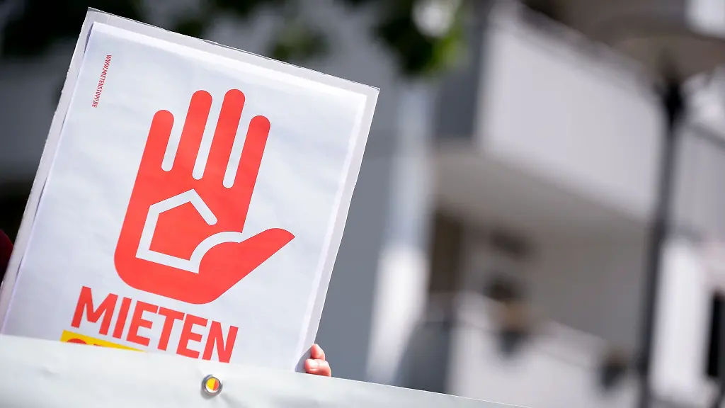 Eine-Demonstrantin-haelt-ein-Plakat-vor-einem-Haus-hoch