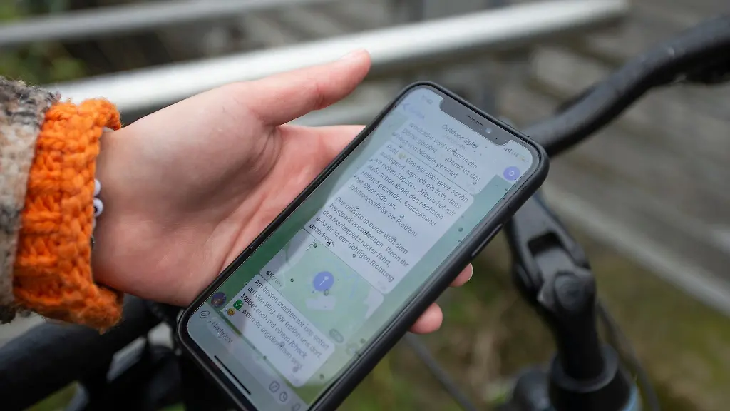 Eine-Teilnehmerin-haelt-ein-Smartphone-mit-Anweisungen-fuer-das-Outdoor-Spiel-in-die-Kamera