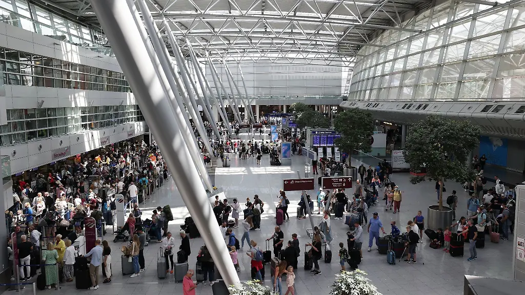 Reisende-stehen-im-Flughafen-Duesseldorf-in-langen-Warteschlangen-an-der-Gepaeckabgabe
